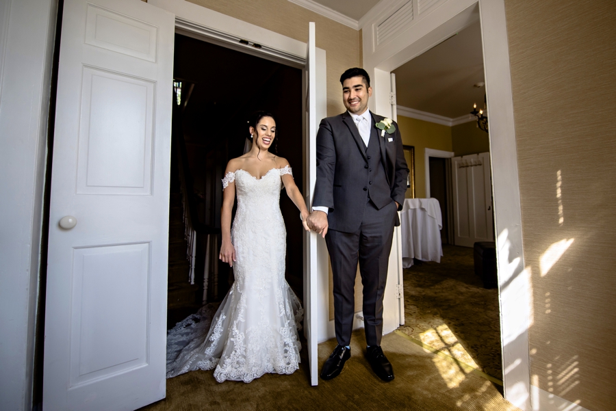 A bride and groom hold hands without seeing each other before the wedding ceremony.